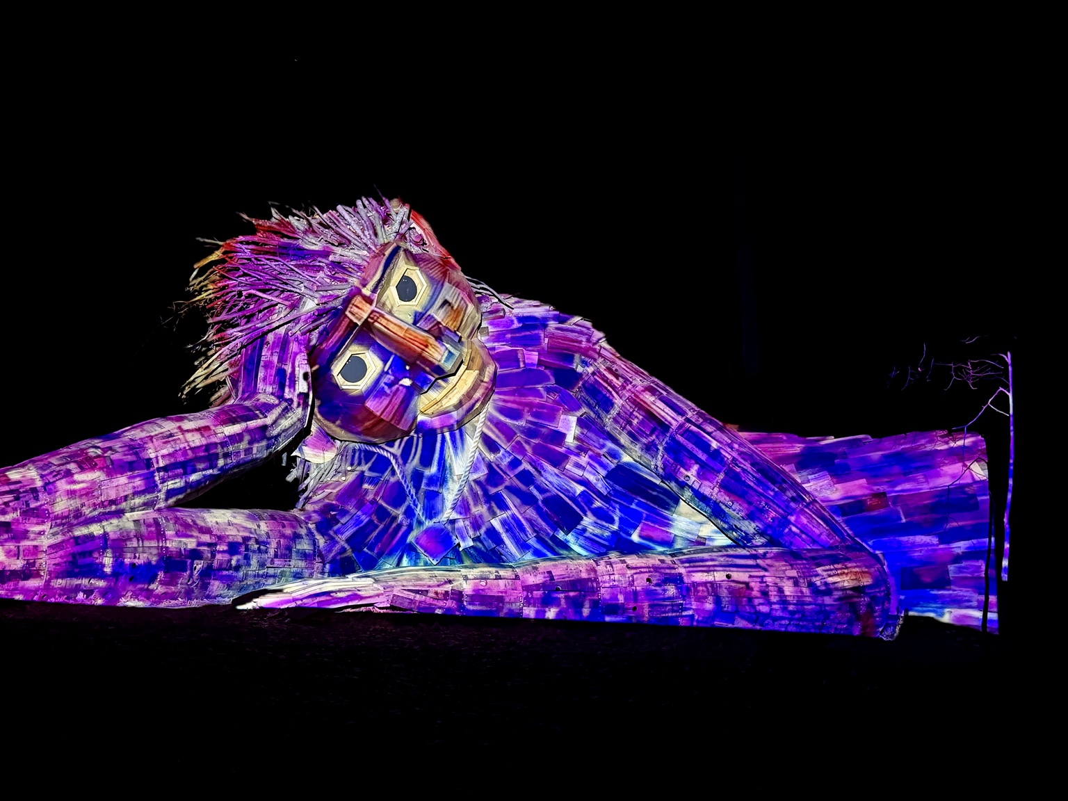 A reclining troll sculpture brought to life with purple and blue projection mapping